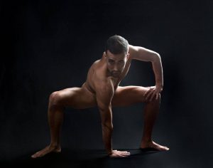 Víctor Óscar Juaranz - Cuerpo desnudo con mano derecha apoyada en el suelo sobre fondo negro - Horizontal - Color